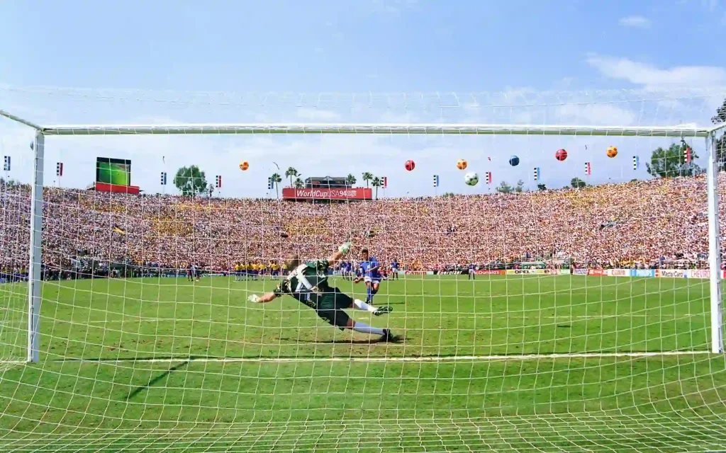 claudio taffarel diving to his left while roberto baggio kicks the ball over the goals