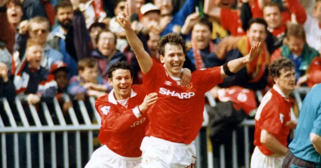 bryan robson celebrating a goal while ryan giggs is trying to catch up to him to congratulate him