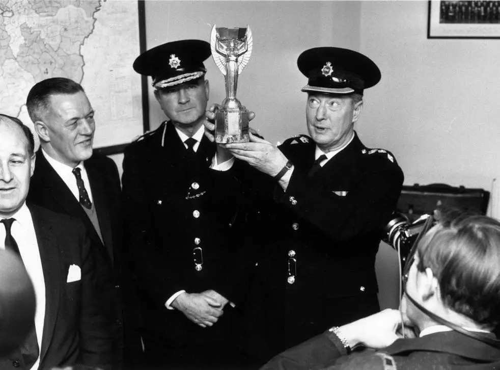 brazil police holding up a replica of the stolen world cup