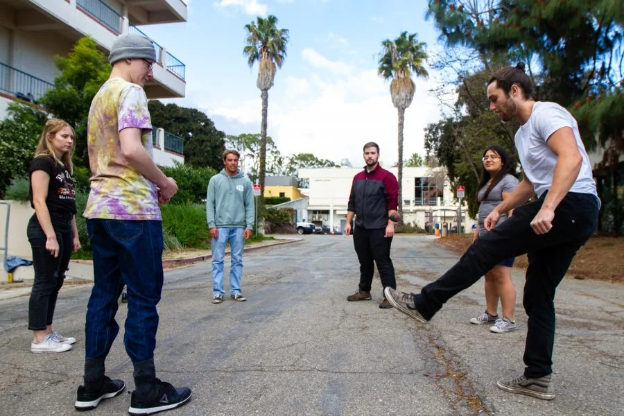 five people in a circle playing hacky sacky